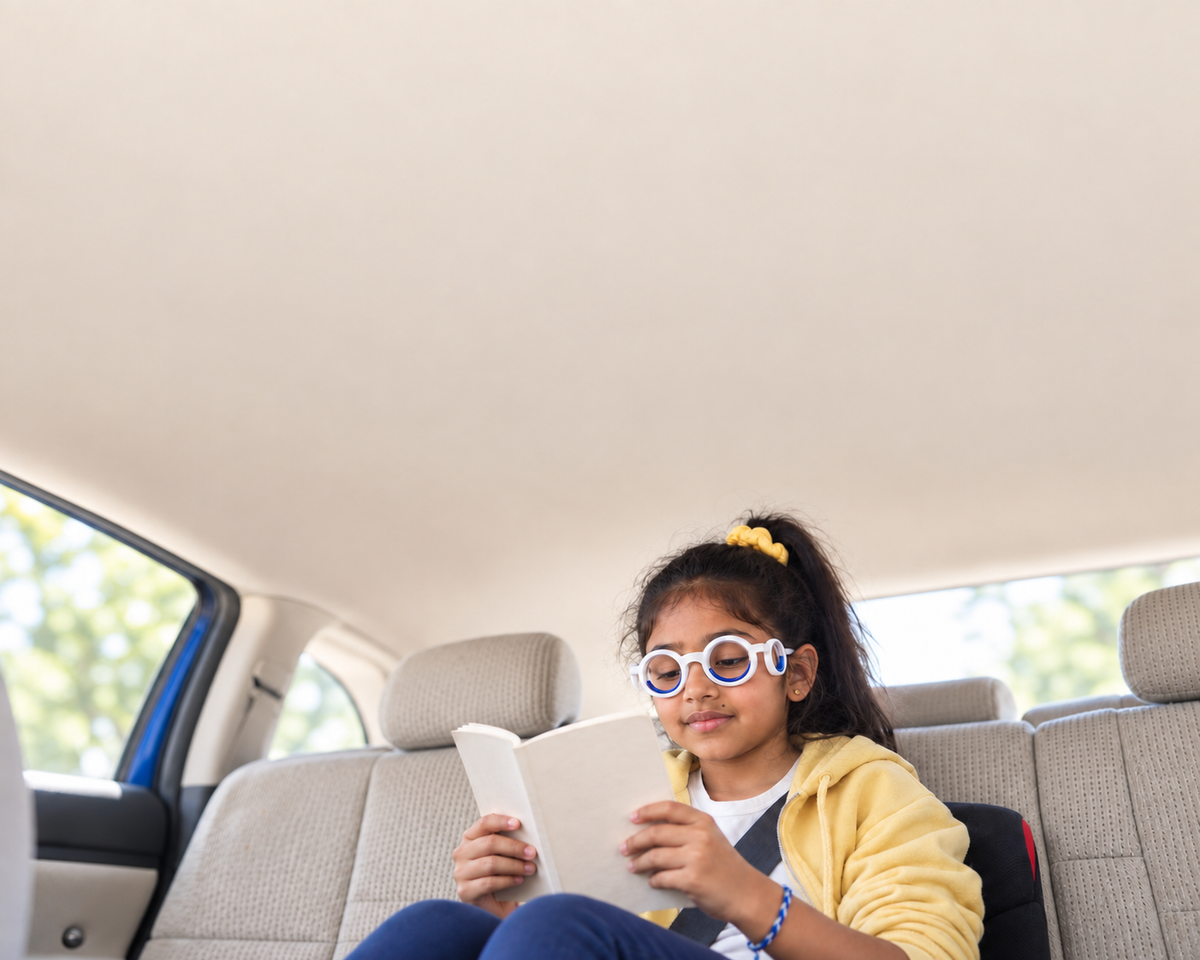 A boy reads a tablet in the back seat
